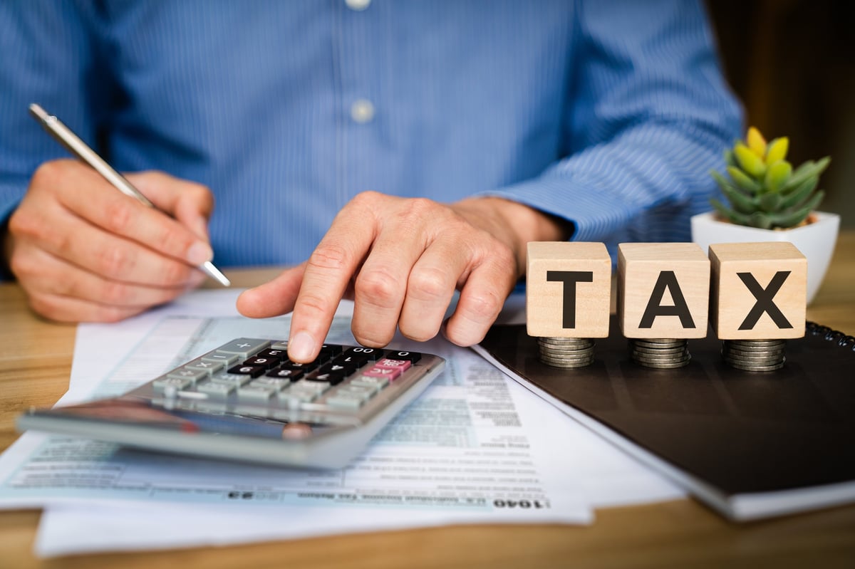 Profesional calculando con calculadora y bloques TAX qué adeudos cubre el Programa de Regularización Fiscal 2026 del SAT